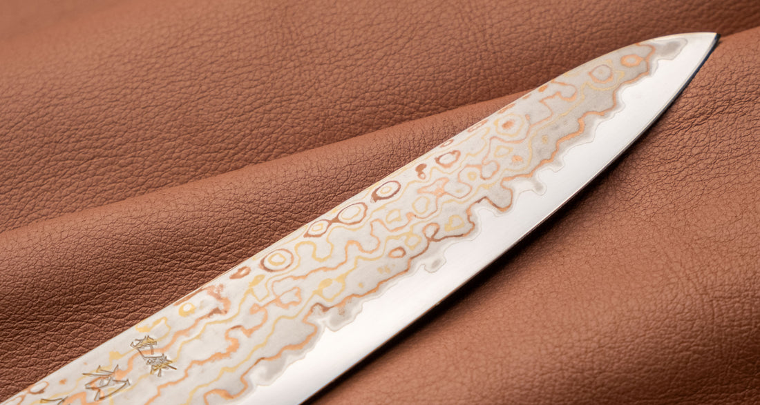 Hayabusa Petty Aogami #2 Rainbow Damascus 150 mm je zadivljujući kolekcionarski predmet, izrađen od Aogami #2 čelika, savršeno zadržava svoju oštrinu, a istovremeno ga je lako oštriti. Krasi ga jedinstveni damast uzorak s blagim mat odsjajem, koji je majstorski postignut pažljivim nanošenjem slojeva bakra i mesinga.