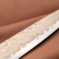 Hayabusa Petty Aogami #2 Rainbow Damascus 150 mm je zadivljujući kolekcionarski predmet, izrađen od Aogami #2 čelika, savršeno zadržava svoju oštrinu, a istovremeno ga je lako oštriti. Krasi ga jedinstveni damast uzorak s blagim mat odsjajem, koji je majstorski postignut pažljivim nanošenjem slojeva bakra i mesinga.