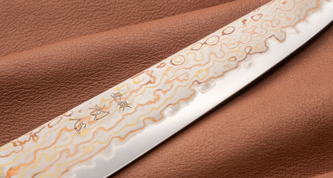 Hayabusa Petty Aogami #2 Rainbow Damascus 150 mm je zadivljujući kolekcionarski predmet, izrađen od Aogami #2 čelika, savršeno zadržava svoju oštrinu, a istovremeno ga je lako oštriti. Krasi ga jedinstveni damast uzorak s blagim mat odsjajem, koji je majstorski postignut pažljivim nanošenjem slojeva bakra i mesinga.