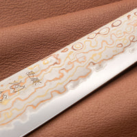 Hayabusa Petty Aogami #2 Rainbow Damascus 150 mm je zadivljujući kolekcionarski predmet, izrađen od Aogami #2 čelika, savršeno zadržava svoju oštrinu, a istovremeno ga je lako oštriti. Krasi ga jedinstveni damast uzorak s blagim mat odsjajem, koji je majstorski postignut pažljivim nanošenjem slojeva bakra i mesinga.