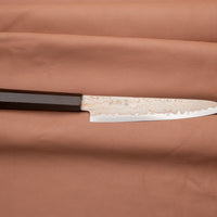 Hayabusa Petty Aogami #2 Rainbow Damascus 150 mm je zadivljujući kolekcionarski predmet, izrađen od Aogami #2 čelika, savršeno zadržava svoju oštrinu, a istovremeno ga je lako oštriti. Krasi ga jedinstveni damast uzorak s blagim mat odsjajem, koji je majstorski postignut pažljivim nanošenjem slojeva bakra i mesinga.