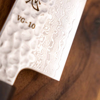 Detalj Hayabusa Gyuto VG-10 Tsuchime Damascus Ebony 210 mm koji prikazuje složeni Tsuchime završetak i elegantan damask uzorak, ističući izradu noža i kvalitetu čelika.