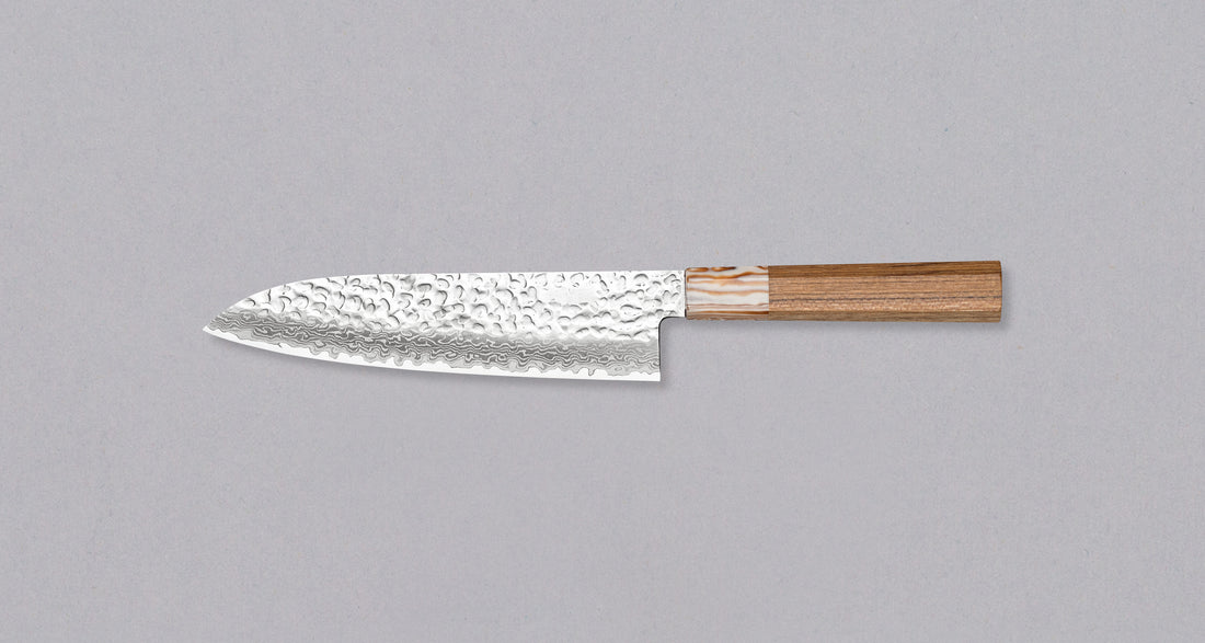 Kotetsu Santoku VG-10 Damascus 180 mm veliki svestrani je nož s vidljivim otiscima čekića i klasičnom japanskom (wa-style) drškom od tikovine. Oduševit će svakega koji cijene i estetski oblikovane kuhinjske posuđe.