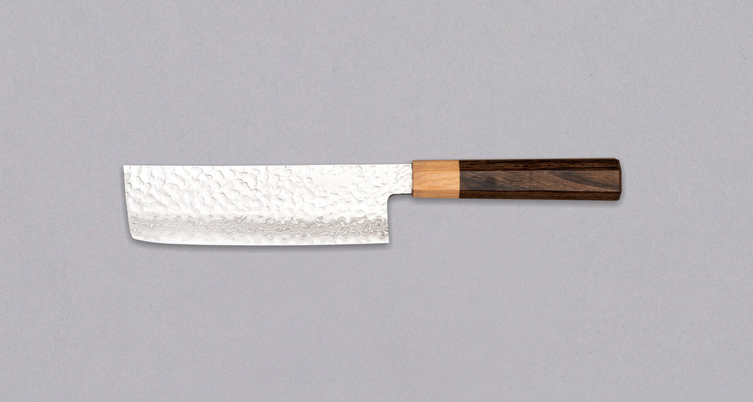 Kotetsu VG-10 Damascus Nakiri 160 mm je nož za povrće s vidljivim otiscima čekića i klasičnom japanskom (wa-style) drškom od pakka drva. Nož je iznimno tanak (1,9 mm) tako da će s lakoćom kliziti kroz sastojke, a odabir VG-10 nehrđajućeg čelika osigurava otpornost na hrđu, izdržljivost i otpornost na habanje.