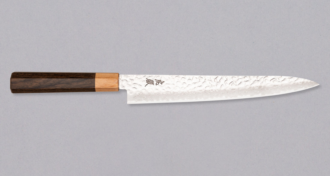 Kotetsu Sujihiki VG-10 Damascus 240 mm je nož za rezanje ribe i mesa s vidljivim otiscima čekića i klasičnom japanskom (wa-style) drškom od pakka drva. Oduševit će svakega koji cijene i estetski oblikovana kuhinjska pomagala. Duga i uska oštrica oblikovana je za rezanje ribe i mesa bez kostiju ili za filetiranje i odstranjivanje kože, jer već jednim potezom precizno odrežemo što želimo. Odabir čelika omogućuje jednostavno brušenje.