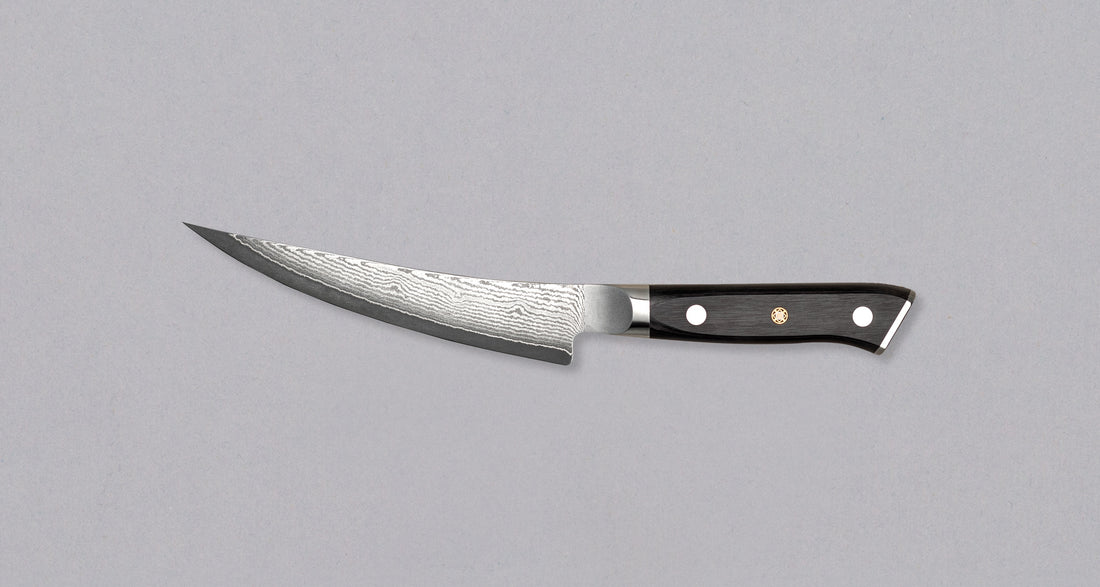 Mcusta Boning VG-10 Black Damascus japanski je nož za otkoštavanje i odvajanje mesa od kostiju, otkoštavanje paradi i filetiranje ribe. Jezgra od nehrđajućeg VG-10 čelika (60-61 HRC) s san-mai laminacijom s mekšim čelikom čini 33 sloja u crnom damast uzorku. Nož ima crnu yo dršku od pakka drva s mozaičkom zakovicom.