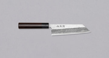 Muneishi Bunka Aogami #2 Damascus 165 mm svestrani je japanski kuhinjski nož namijenjen za pripremu mesa, ribe i povrća. Ovaj nož se drži tradicije, ali je i nadgrađuje: Oblik bunka, visokougljični čelik Aogami #2, udobna ovalna drška od palisandera. Prijelaz s migaki uzorka na magličast damast uzorak daje dašak elegancije.