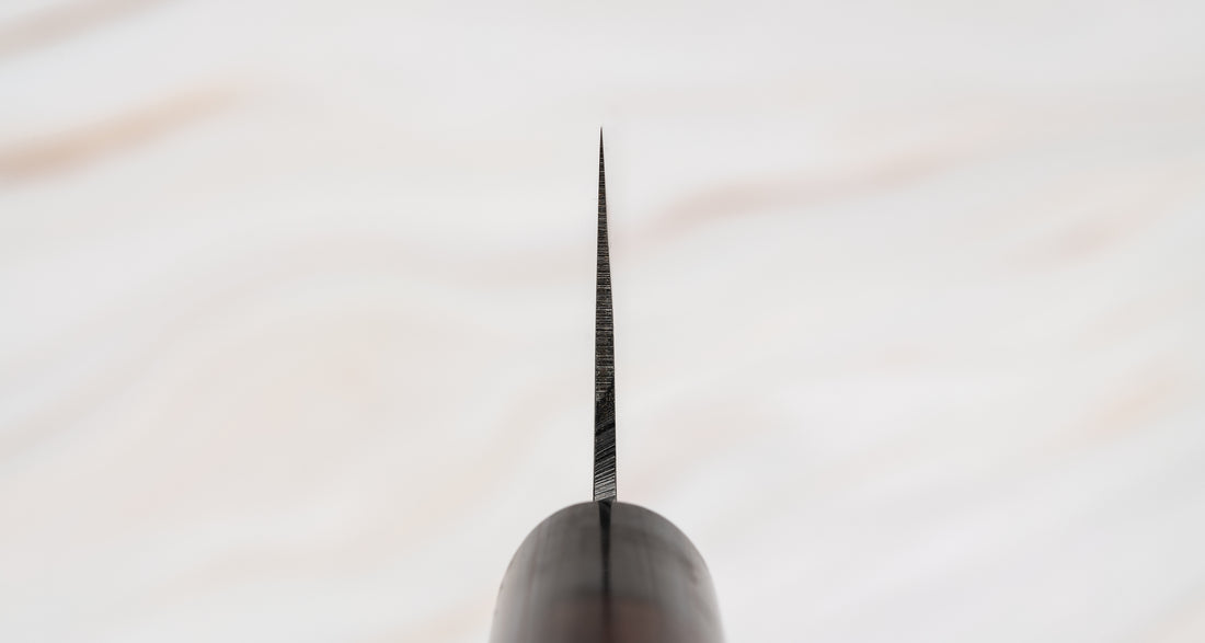 Muneishi Bunka Aogami #2 Damascus 165 mm svestrani je japanski kuhinjski nož namijenjen za pripremu mesa, ribe i povrća. Ovaj nož se drži tradicije, ali je i nadgrađuje: Oblik bunka, visokougljični čelik Aogami #2, udobna ovalna drška od palisandera. Prijelaz s migaki uzorka na magličast damast uzorak daje dašak elegancije.