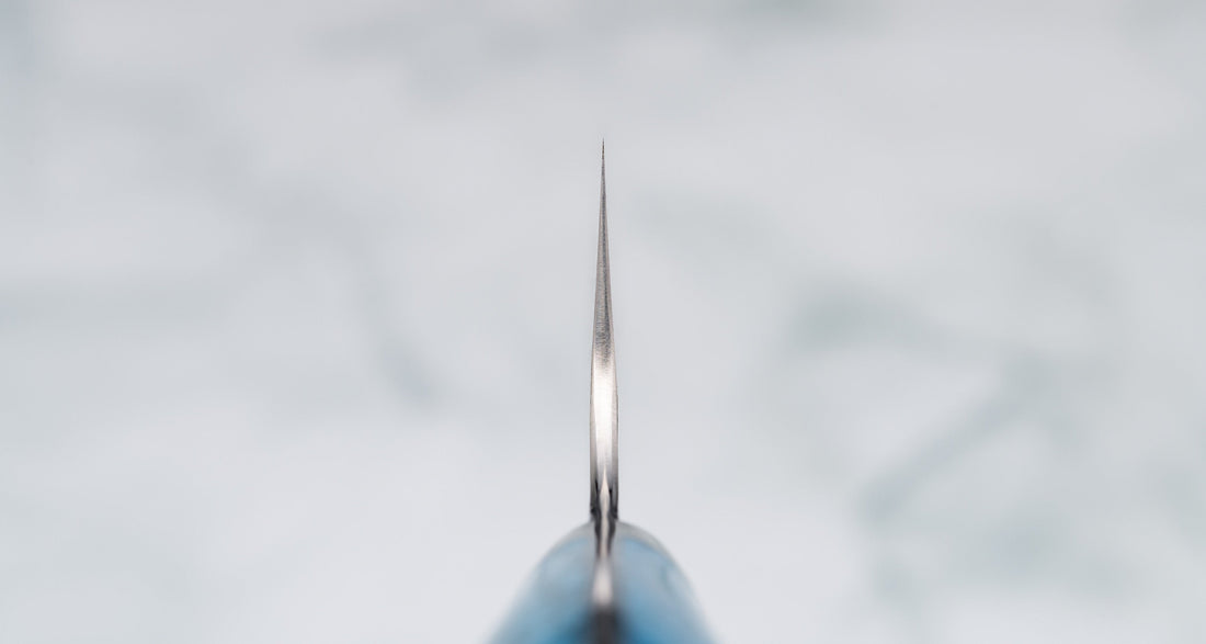 Nigara Kiri-Gyuto SG2 Migaki Tsuchime Turquoise 210 mm višenamjenski je japanski kuhinjski nož, pogodan za pripremu mesa, ribe i povrća. Jezgra od SG2 praškastog čelika i hamaguri presjek profila osiguravaju dugotrajnu oštrinu i minimalno održavanje. Odrezani kiritsuke vršak pomaže nam pregledati i precizno rezati hranu.
