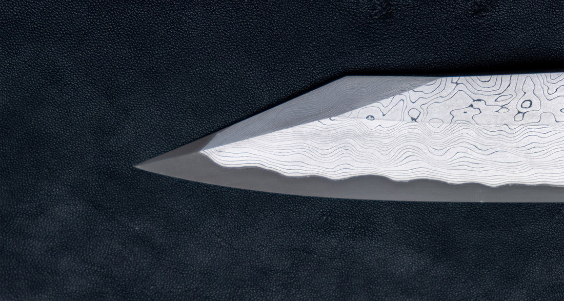 Nigara Kurozome Kiritsuke Yanagiba Aogami #2 Damascus 240 mm tradicionalni je japanski nož koji se koristi za pripremu ribe (osobito za sašimi i nigiri suši). Duga oštrica omogućuje lijepe i duge pokrete, a podrezan vršak precizan završetak reza.