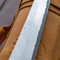Nigara Kurozome Kiritsuke Yanagiba Aogami #2 Damascus 240 mm tradicionalni je japanski nož koji se koristi za pripremu ribe (osobito za sašimi i nigiri suši). Duga oštrica omogućuje lijepe i duge pokrete, a podrezan vršak precizan završetak reza.
