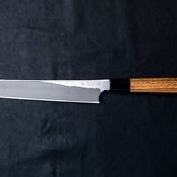 Nigara Kurozome Kiritsuke Yanagiba Aogami #2 Damascus 240 mm tradicionalni je japanski nož koji se koristi za pripremu ribe (osobito za sašimi i nigiri suši). Duga oštrica omogućuje lijepe i duge pokrete, a podrezan vršak precizan završetak reza.