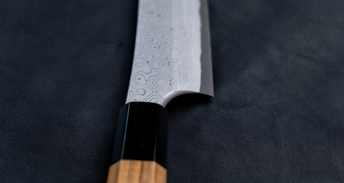 Nigara Kurozome Kiritsuke Yanagiba Aogami #2 Damascus 270 mm tradicionalni je japanski nož koji se koristi za pripremu ribe, posebno za sašimi i nigiri suši. Duljina noža omogućuje korisniku rezanje ribljeg filea jednim potezom, što zajedno s jednostrano brušenom oštricom doprinosi briljantno glatkim kriškama sašimija.