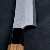 Nigara Kurozome Kiritsuke Yanagiba Aogami #2 Damascus 270 mm tradicionalni je japanski nož koji se koristi za pripremu ribe, posebno za sašimi i nigiri suši. Duljina noža omogućuje korisniku rezanje ribljeg filea jednim potezom, što zajedno s jednostrano brušenom oštricom doprinosi briljantno glatkim kriškama sašimija.