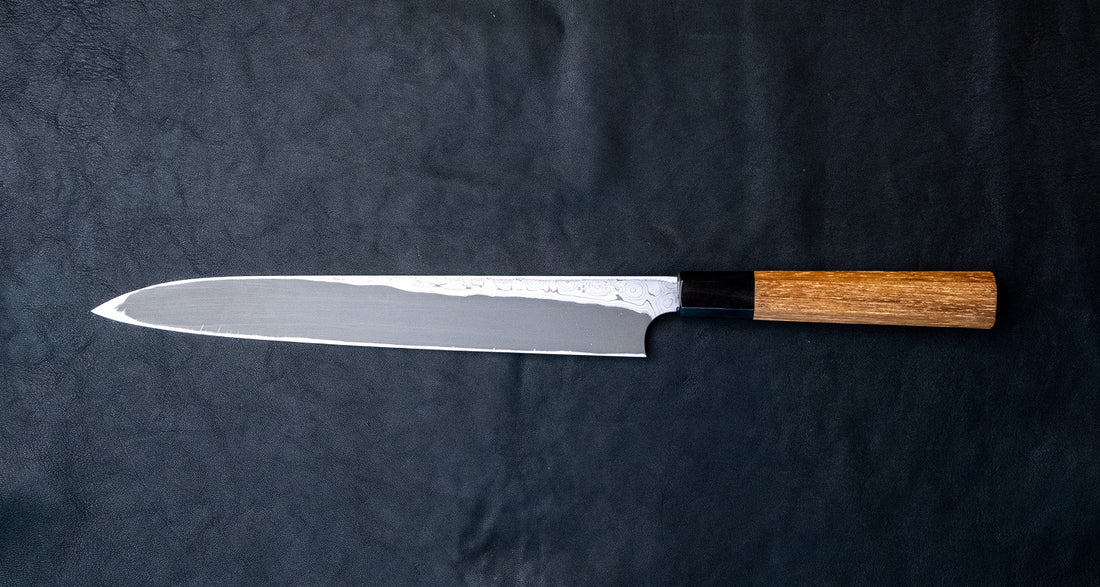 Nigara Kurozome Kiritsuke Yanagiba Aogami #2 Damascus 270 mm tradicionalni je japanski nož koji se koristi za pripremu ribe, posebno za sašimi i nigiri suši. Duljina noža omogućuje korisniku rezanje ribljeg filea jednim potezom, što zajedno s jednostrano brušenom oštricom doprinosi briljantno glatkim kriškama sašimija.
