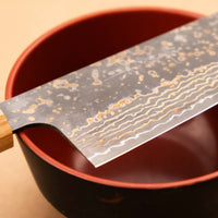 Saji Santoku VG-10 Gold RWO 165 mm je svestrani japanski kuhinjski nož, prikladan za pripremu mesa, ribe i povrća. Međutim, činili bismo mu krivo kad bismo ga nazvali samo kuhinjskim nožem jer on je zaista izniman primjer japanske kovačke vještine – od njegovog izgleda pa sve do specifičnih detalja.