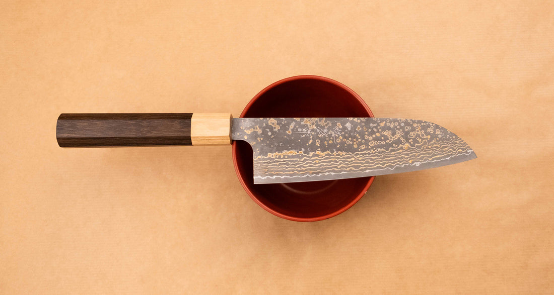 Saji Santoku VG-10 Gold RWO 165 mm je svestrani japanski kuhinjski nož, prikladan za pripremu mesa, ribe i povrća. Međutim, činili bismo mu krivo kad bismo ga nazvali samo kuhinjskim nožem jer on je zaista izniman primjer japanske kovačke vještine – od njegovog izgleda pa sve do specifičnih detalja.