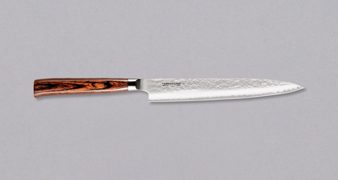 Tamahagane "TSUBAME" Sashimi-Slicer 210mm Sashimi 210 mm: Duga i uska oštrica je prikladna za rezanje tankih komada mesa i ribe. Ovaj je nož izvrstan za žar i sushi majstore te za sve ljubitelje odličnih odrezaka! Noževe Tamahagane izrađuju u Nigati u Japanu, u regiji poznatoj po proizvodima od čelika. Napravljeni su na tradicionalan način uz upotrebu moderne tehnologije.