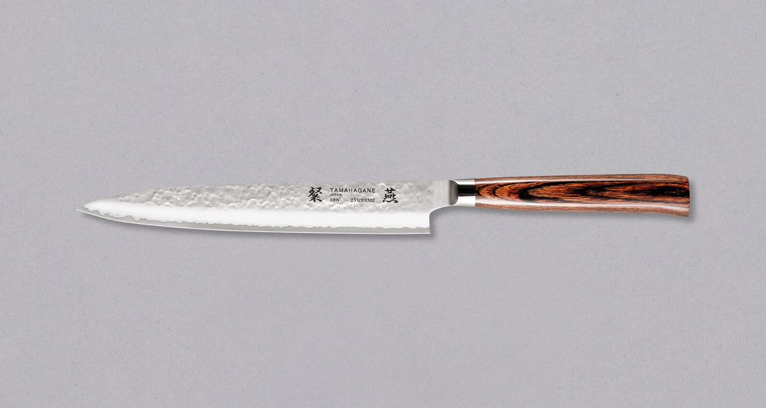 Tamahagane "TSUBAME" Sashimi-Slicer 210mmSashimi 210 mm: Duga i uska oštrica je prikladna za rezanje tankih komada mesa i ribe. Ovaj je nož izvrstan za žar i sushi majstore te za sve ljubitelje odličnih odrezaka! Noževe Tamahagane izrađuju u Nigati u Japanu, u regiji poznatoj po proizvodima od čelika. Napravljeni su na tradicionalan način uz upotrebu moderne tehnologije.
