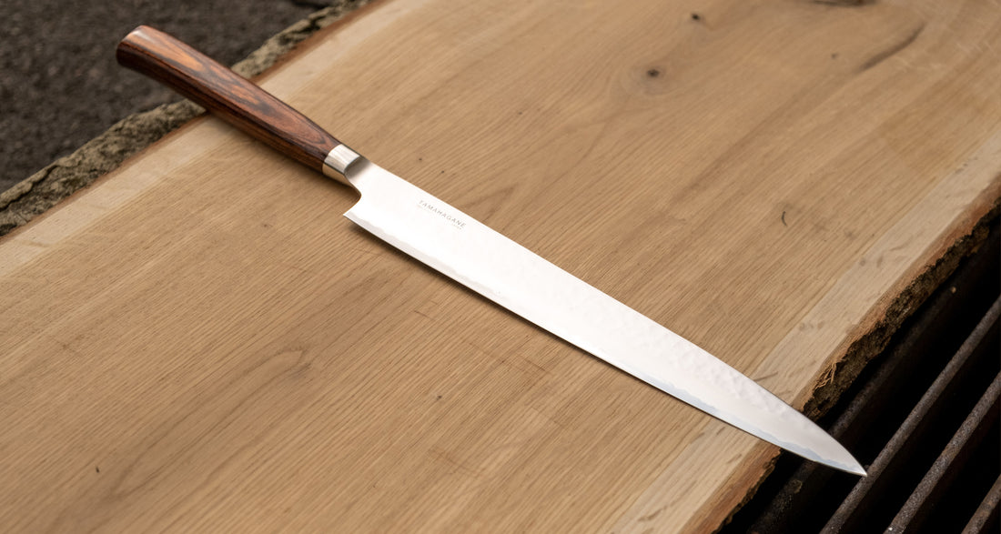 Sashimi-SLicer 240 mm: Duga i uska oštrica je prikladna za rezanje tankih komada mesa i ribe. Ovaj je nož izvrstan za žar i sushi majstore te za sve ljubitelje odličnih odrezaka! Noževe Tamahagane izrađuju u Nigati u Japanu, u regiji poznatoj po proizvodima od čelika. Napravljeni su na tradicionalan način uz upotrebu moderne tehnologije.