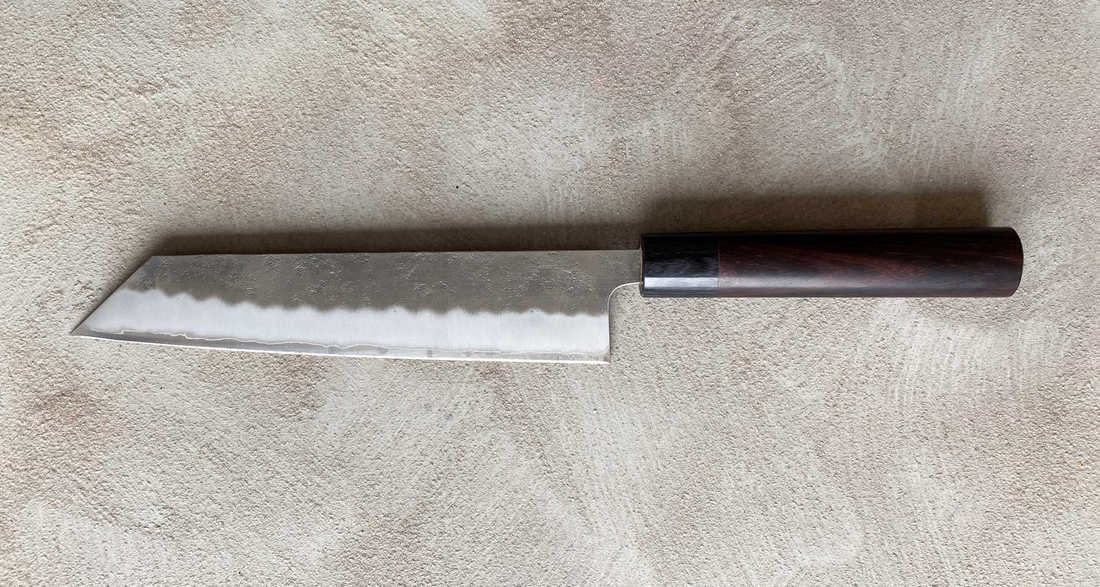 Hokiyama Ginsanko Rosewood Kiritsuke 210 mm_2   Kiritsuke je višenamjenski japanski kuhinjski nož - dužina 210 mm optimalna je za sjeckanje povrća i rezanje većih komada mesa. Srce noža je Silver Steel III čelik, tvrdoće cca 63 HRC koji zovu još i Ginsan Steel ili Ginsanko. Glavna osobina ovog čelika je da se odlično suprotstavlja hrđanju.