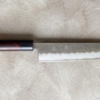 Hokiyama Ginsanko Rosewood Kiritsuke 210 mm_3 Kiritsuke je višenamjenski japanski kuhinjski nož - dužina 210 mm optimalna je za sjeckanje povrća i rezanje većih komada mesa. Srce noža je Silver Steel III čelik, tvrdoće cca 63 HRC koji zovu još i Ginsan Steel ili Ginsanko. Glavna osobina ovog čelika je da se odlično suprotstavlja hrđanju.