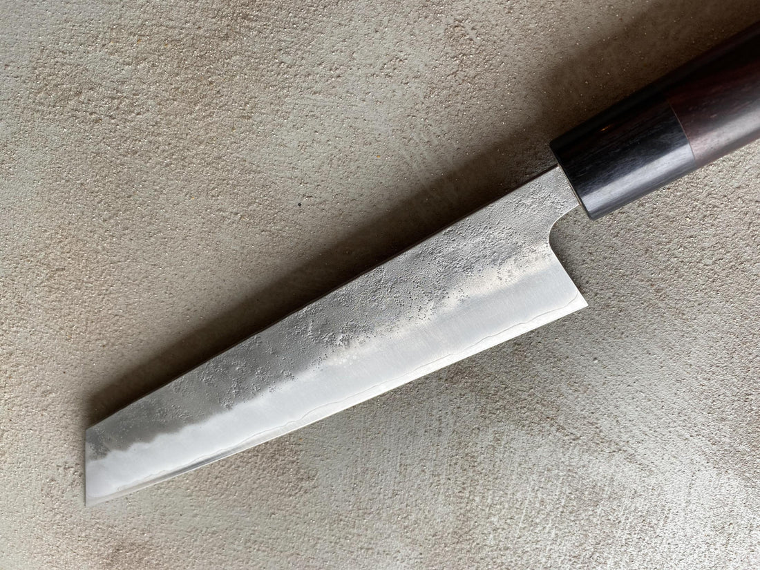 Hokiyama Ginsanko Rosewood Kiritsuke 210 mm_5  Kiritsuke je višenamjenski japanski kuhinjski nož - dužina 210 mm optimalna je za sjeckanje povrća i rezanje većih komada mesa. Srce noža je Silver Steel III čelik, tvrdoće cca 63 HRC koji zovu još i Ginsan Steel ili Ginsanko. Glavna osobina ovog čelika je da se odlično suprotstavlja hrđanju.