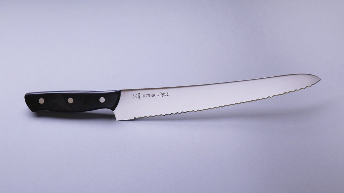 Tojiro Pankiri (nož za kruh) 270 mm_2  Ručno kovan nož za kruh Tojiro s kompaktnom drškom od crnog drveta i dugom oštricom (270 mm) nezamjenjiv je alat za profesionalne kuhare ili strastvene kuhare kod kuće. Oštrica je izrađena od molibden vanadijevog čelika s 57–59 HRC i je neosjetljiva na vanjske faktore i jako je oštra.