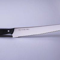 Tojiro Pankiri (nož za kruh) 270 mm_2 Ručno kovan nož za kruh Tojiro s kompaktnom drškom od crnog drveta i dugom oštricom (270 mm) nezamjenjiv je alat za profesionalne kuhare ili strastvene kuhare kod kuće. Oštrica je izrađena od molibden vanadijevog čelika s 57–59 HRC i je neosjetljiva na vanjske faktore i jako je oštra.