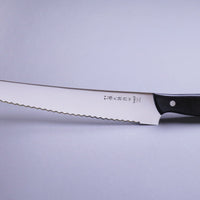 Tojiro Pankiri (nož za kruh) 270 mm_3 Ručno kovan nož za kruh Tojiro s kompaktnom drškom od crnog drveta i dugom oštricom (270 mm) nezamjenjiv je alat za profesionalne kuhare ili strastvene kuhare kod kuće. Oštrica je izrađena od molibden vanadijevog čelika s 57–59 HRC i je neosjetljiva na vanjske faktore i jako je oštra.