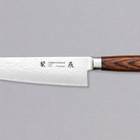 Tamahagane "TSUBAME" Kengata 190 mm_1Tamahagane San Kengata 190 mm ili Bunka je svestran kuhinjski nož koji će blistati prilikom sjeckanja i rezanja na kuhinjskoj dasci. Veličina oštrice je 190 mm. Noževe Tamahagane izrađuju u Nigati u Japanu, u regiji poznatoj po proizvodima od čelika. Napravljeni su na tradicionalan način uz upotrebu moderne tehnologije.