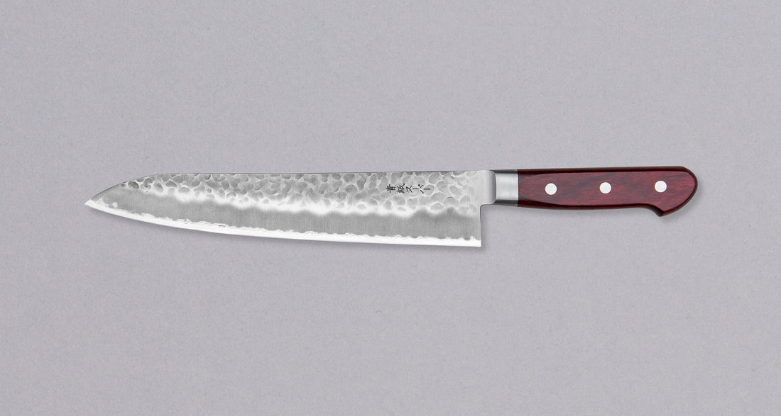 Tsunehisa Gyuto AS Tsuchime 240 mm svestrani je japanski kuhinjski nož za pripremu mesa, ribe i povrća. Gyuto u prijevodu znači 'goveđi mač' što govori o njegovoj naklonjenosti rezanju mesa. Pogotovo duži gyuto noževi – poput ovog ljepotana iz kovačnice Tshunehisa – posebno zablistaju pri rezanju većih komada mesa i pripremi sašimija, izvrsni su, naravno, i pri pripremi svih ostalih namirnica.