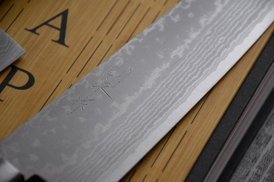 Etsu Village Santoku Damascus Black 170 mm_2  Ručno kovan Kunio Masutani damask nož. Santoku koristi se za rezanje povrća, ribe i mesa. Oblik i dužina su primjerni za manji svestrani kuhinjski nož koji će zablistati prilikom rezanja i sjeckanja na kuhinjskoj dasci. Za domaću te profesionalnu upotrebu.
