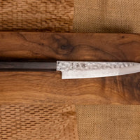 Hayabusa Petty VG-10 Tsuchime Damascus Ebony 150 mm je manji višenamjenski nož s vidljivim otiscima čekića, elegantnim damask uzorkom i klasičnom japanskom drškom (wa-stil) izrađenom od ebanovina drveta.