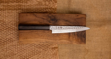 Hayabusa Petty VG-10 Tsuchime Damascus Ebony 150 mm je manji višenamjenski nož s vidljivim otiscima čekića, elegantnim damask uzorkom i klasičnom japanskom drškom (wa-stil) izrađenom od ebanovina drveta.