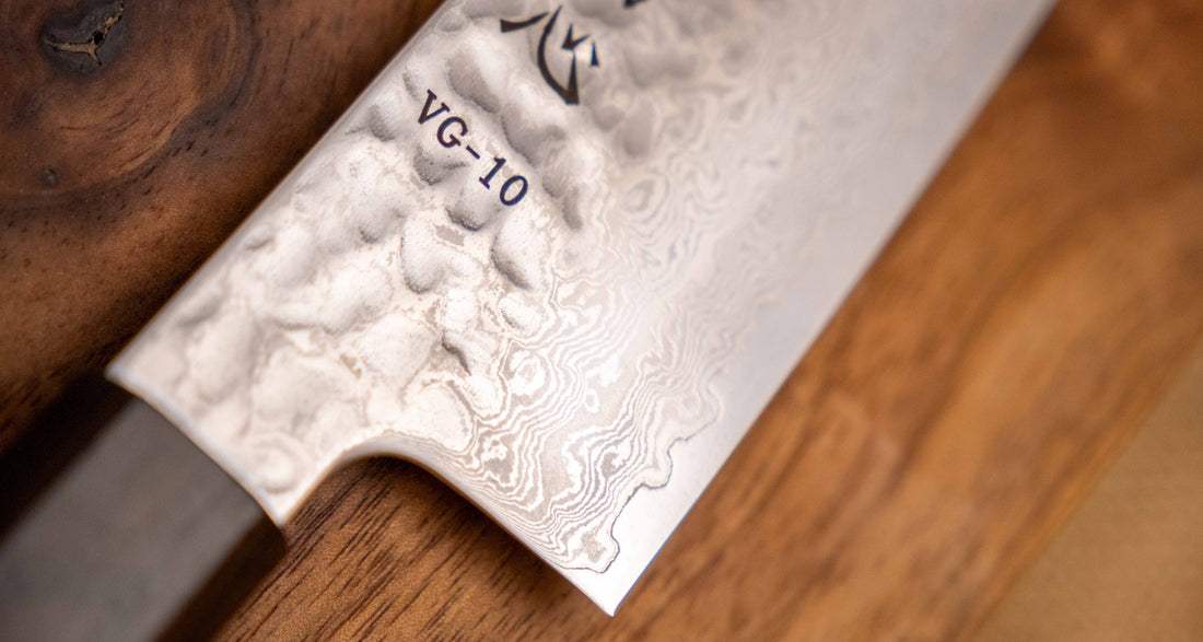 Detaljan prikaz površine i teksture noža Hayabusa Santoku VG-10 Tsuchime Damascus Ebony 180 mm, s prepoznatljivim damask uzorkom i čekićem otisnutom teksturom, koja smanjuje lijepljenje hrane na oštricu