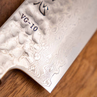 Detaljan prikaz površine i teksture noža Hayabusa Santoku VG-10 Tsuchime Damascus Ebony 180 mm, s prepoznatljivim damask uzorkom i čekićem otisnutom teksturom, koja smanjuje lijepljenje hrane na oštricu