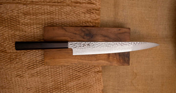 Detalj desne strane noža Hayabusa Sujihiki VG-10 Tsuchime Damascus 270 mm, koji prikazuje cijelu duljinu uske oštrice s složenim damask uzorkom i tsuchime teksturom.