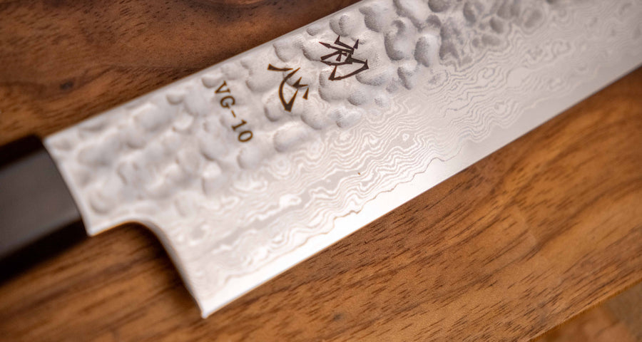 Detalj desne strane noža Hayabusa Sujihiki VG-10 Tsuchime Damascus 270 mm, koji prikazuje cijelu duljinu uske oštrice s složenim damask uzorkom i tsuchime teksturom.