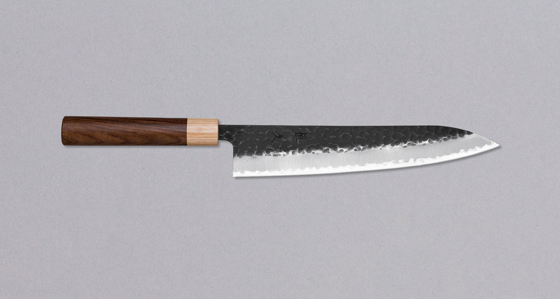 Morado Gyuto je odličan ručno kovan nož sa crnom Kuro-uchi patinom i tragovima čekića. Gyuto je japanski oblik tradicionalnih europskih chef noževa. Dužina 240 mm optimalna je za sjeckanje povrća i rezanje većih komada mesa. Zbog dužine ga preporučujemo iskusnim kuharima odnosno svima koji su navikli na rezanje dužim noževima.