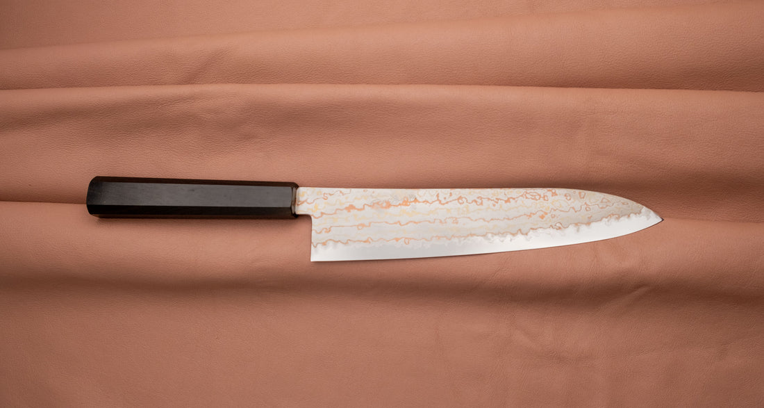 Hayabusa Gyuto Aogami #2 Rainbow Damascus 210 mm je zadivljujući kolekcionarski predmet, izrađen od Aogami #2 čelika, savršeno zadržava svoju oštrinu, a istovremeno ga je lako oštriti. Krasi ga jedinstveni damast uzorak s blagim mat odsjajem, koji je majstorski postignut pažljivim nanošenjem slojeva bakra i mesinga. 