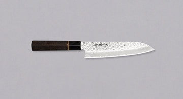 Kawamura Santoku Damascus svestrani je japanski kuhinjski nož. Jezgra je izrađena od čelika AUS-10 i obavijena u slojeve damaščanskog čelika. Gornji dio oštrice krase otisci čekića. Tradicionalna japanska drška izrađena je od paljenog drva kestena s prstenom od bivoljeg roga.