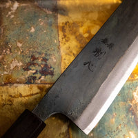 Detaljan prikaz kuro-uchi površine, kanji gravura i pete noža Kokugei Gyuto Aogami #1 Kuro-uchi Ebony 210 mm, naglašavajući ručno kovani karakter.