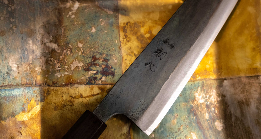 Detaljan prikaz kuro-uchi površine, kanji gravura i pete noža Kokugei Gyuto Aogami #1 Kuro-uchi Ebony 210 mm, naglašavajući ručno kovani karakter.