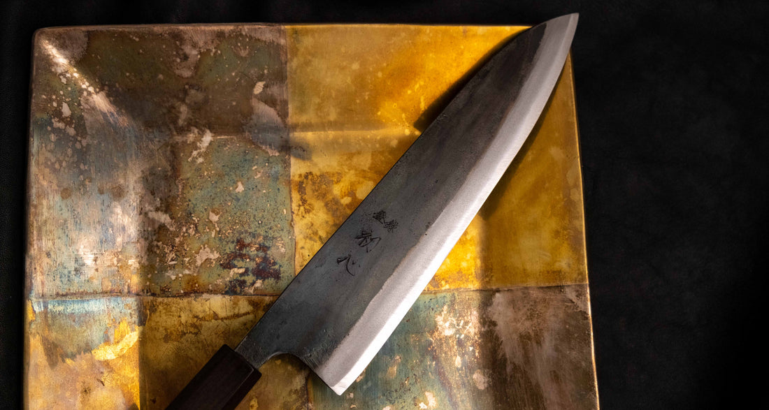 Detaljan prikaz kuro-uchi površine, kanji gravura i pete noža Kokugei Gyuto Aogami #1 Kuro-uchi Ebony 210 mm, naglašavajući ručno kovani karakter.