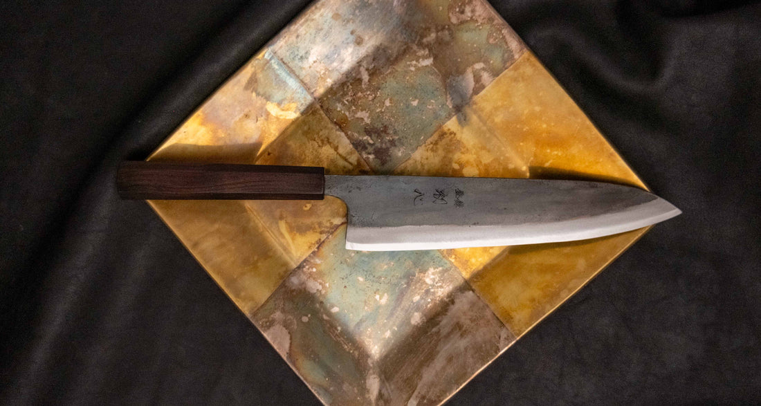 Kokugei Gyuto Aogami #1 Kuro-uchi Ebony 210 mm svestrani je japanski kuhinjski nož namijenjen pripremi mesa, ribe i povrća. Nož ima distalno suženu pozadinu i rustikalnu crnu kuro-uchi površinsku obradu koja odražava tradicionalnu estetiku ručno kovanih japanskih noževa.