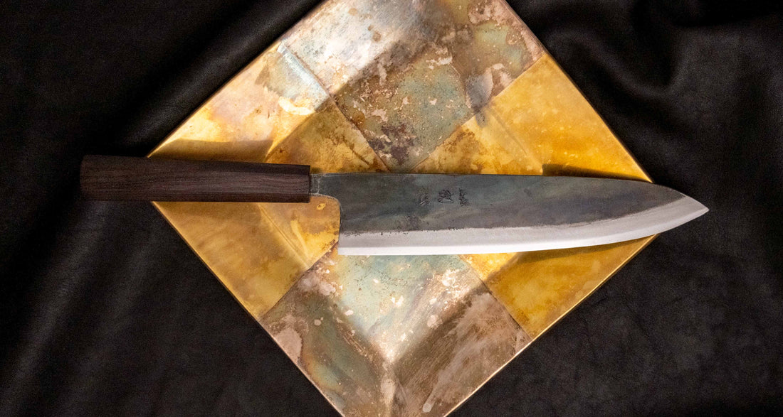 Kokugei Gyuto Aogami #1 Kuro-uchi Ebony 240 mm svestrani je japanski kuhinjski nož namijenjen pripremi mesa, ribe i povrća. Nož ima distalno suženu pozadinu i rustikalnu crnu kuro-uchi površinsku obradu koja odražava tradicionalnu estetiku ručno kovanih japanskih noževa.