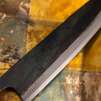 Detaljan prikaz kuro-uchi površine, kanji gravura i pete noža Kokugei Gyuto Aogami #1 Kuro-uchi Ebony 240 mm, naglašavajući ručno kovani karakter.