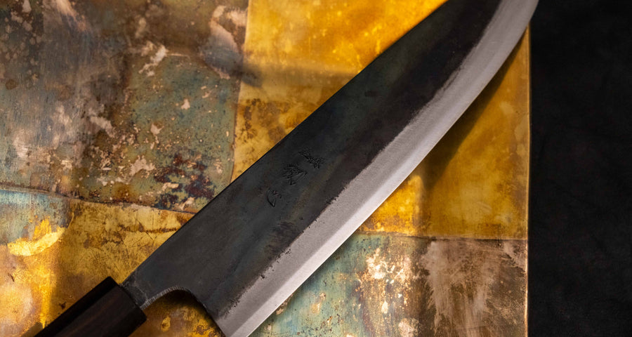 Detaljan prikaz kuro-uchi površine, kanji gravura i pete noža Kokugei Gyuto Aogami #1 Kuro-uchi Ebony 240 mm, naglašavajući ručno kovani karakter.