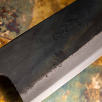 Detaljan prikaz kuro-uchi površine, kanji gravura i pete noža Kokugei Gyuto Aogami #1 Kuro-uchi Ebony 240 mm, naglašavajući ručno kovani karakter.